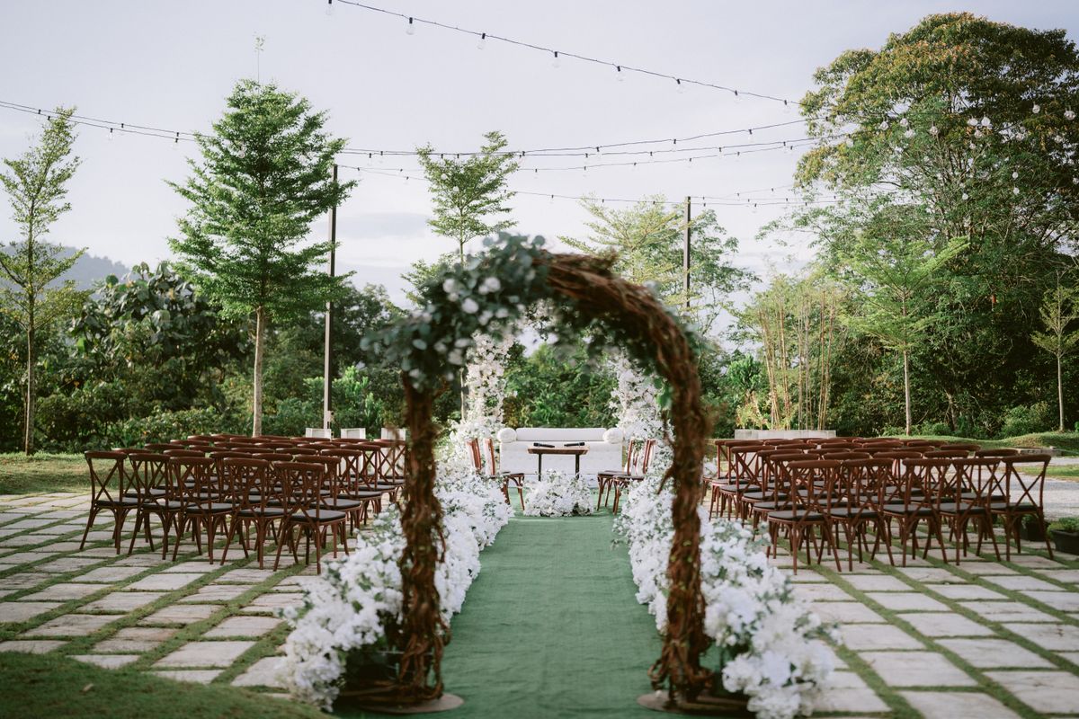 Outdoor celebration setting with an arch, seating and warm lighting in a garden