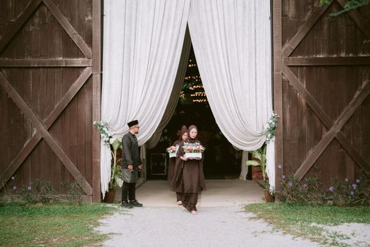 A beautiful traditional wedding ceremony with guests dressed in elegant attire at a rustic barn venue.