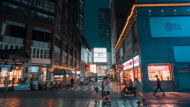 Bustling night scene in Chengdu's city center with illuminated shops and pedestrians.