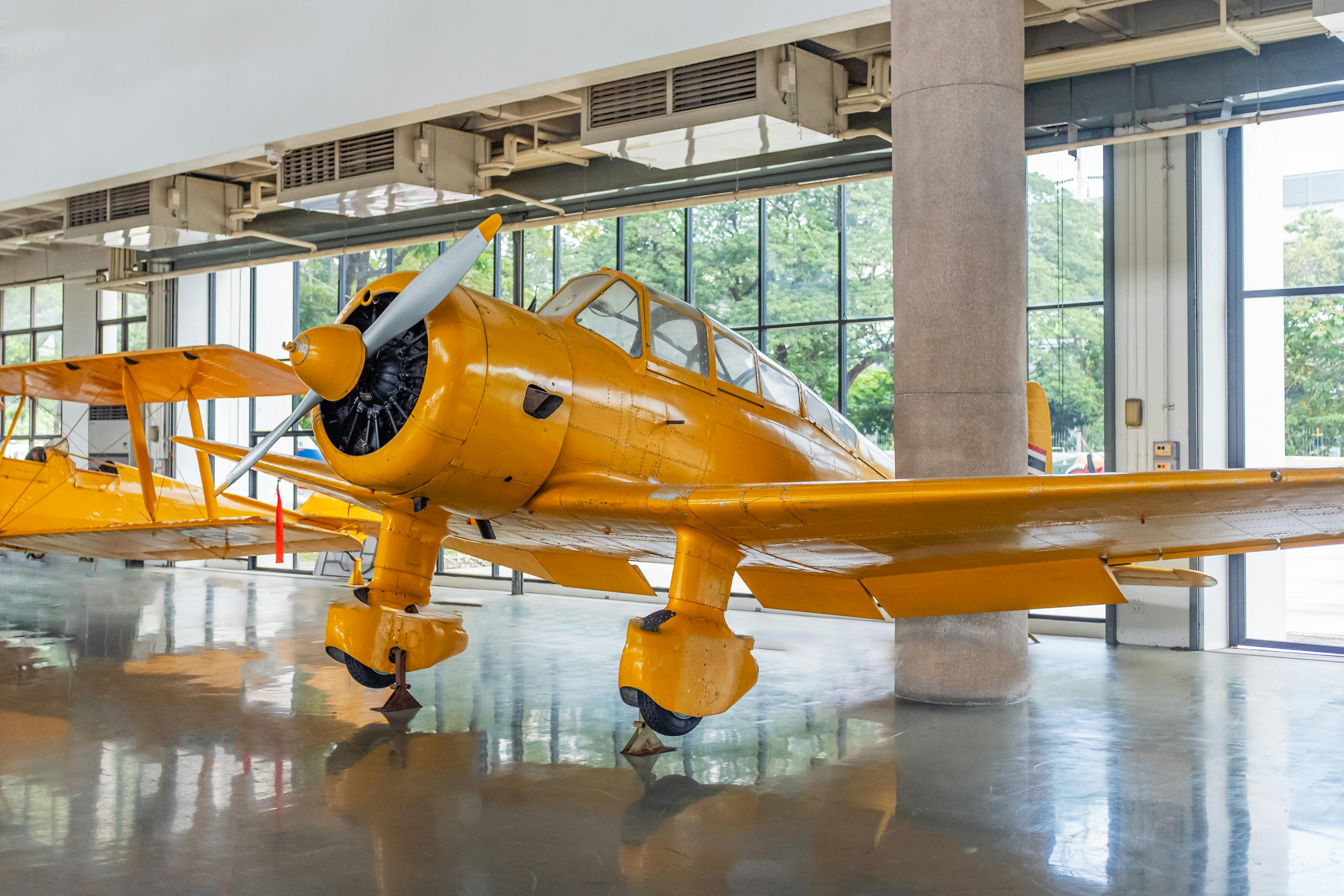 Yellow vintage aircraft showcased in a museum setting with natural light.