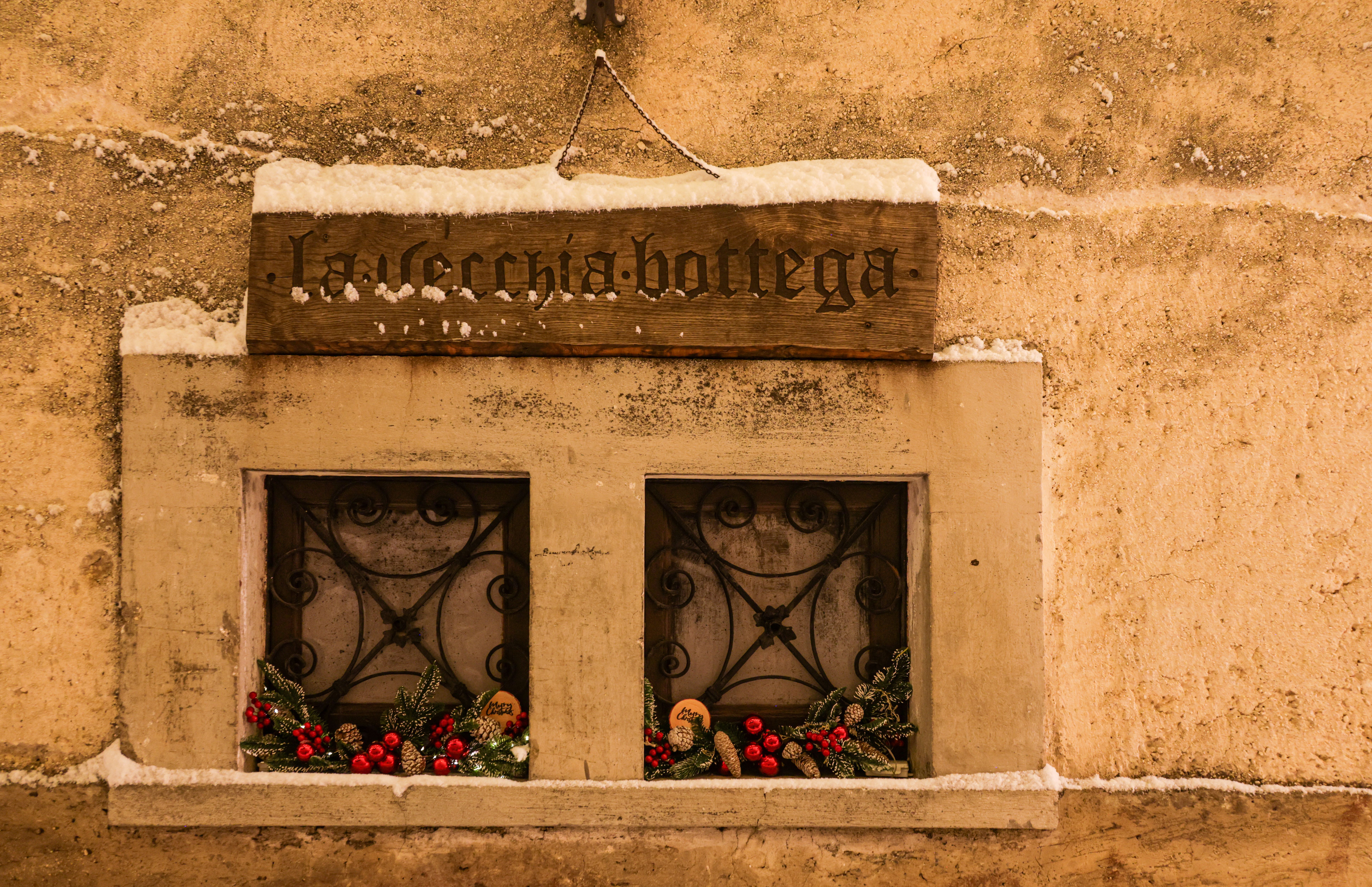 A cozy rustic shopfront decorated for the winter season with snow and vibrant festive ornaments.