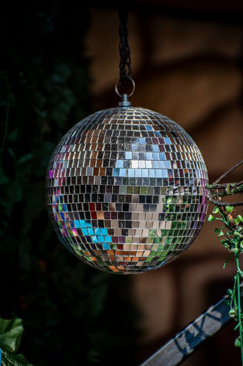 Free Reflective disco ball hanging outdoors with colorful reflections and dark foliage. Stock Photo