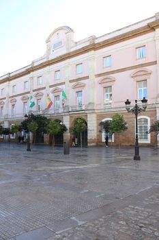 The elegant facade of the Diputación de Cádiz with flags displayed, showcasing historical architecture.