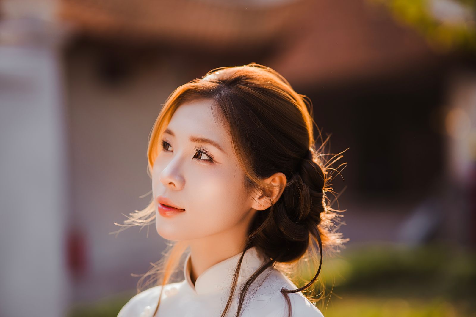 Profile portrait of a woman with glowing skin illuminated by warm golden hour sunlight.
