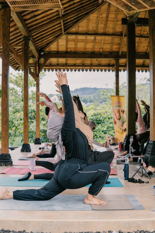 Free Group practicing yoga in a beautiful outdoor setting in a traditional Indonesian pavilion. Stock Photo