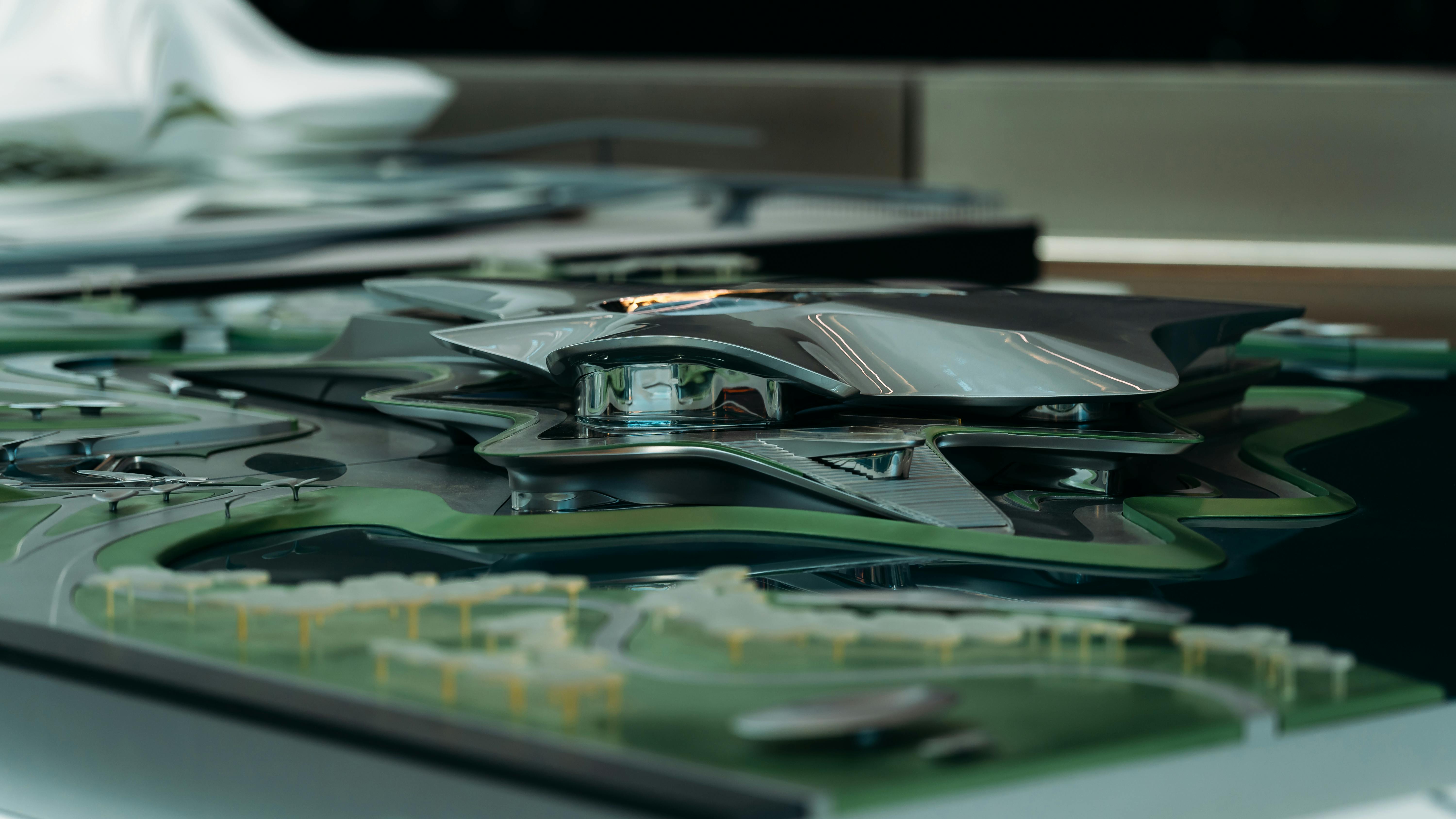 Gratis Model arsitektur ramping dan futuristik yang menampilkan desain metalik dengan lanskap hijau di sekitarnya. Foto Stok