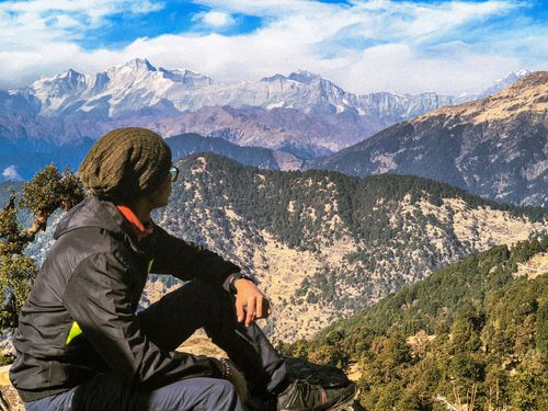Free A trekker sitting on a hill in Chopta, India, admiring the scenic Himalayan mountains. Stock Photo
