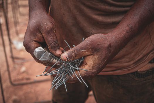 Detailed image of a craftsman holding wires, focusing on their hands and tools in Ife, Nigeria.