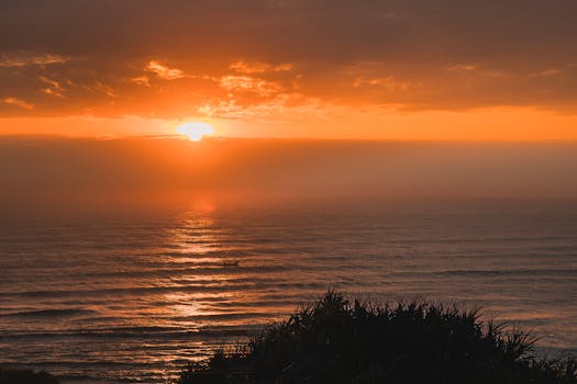 A stunning sunset casting golden hues over the calm ocean waters.