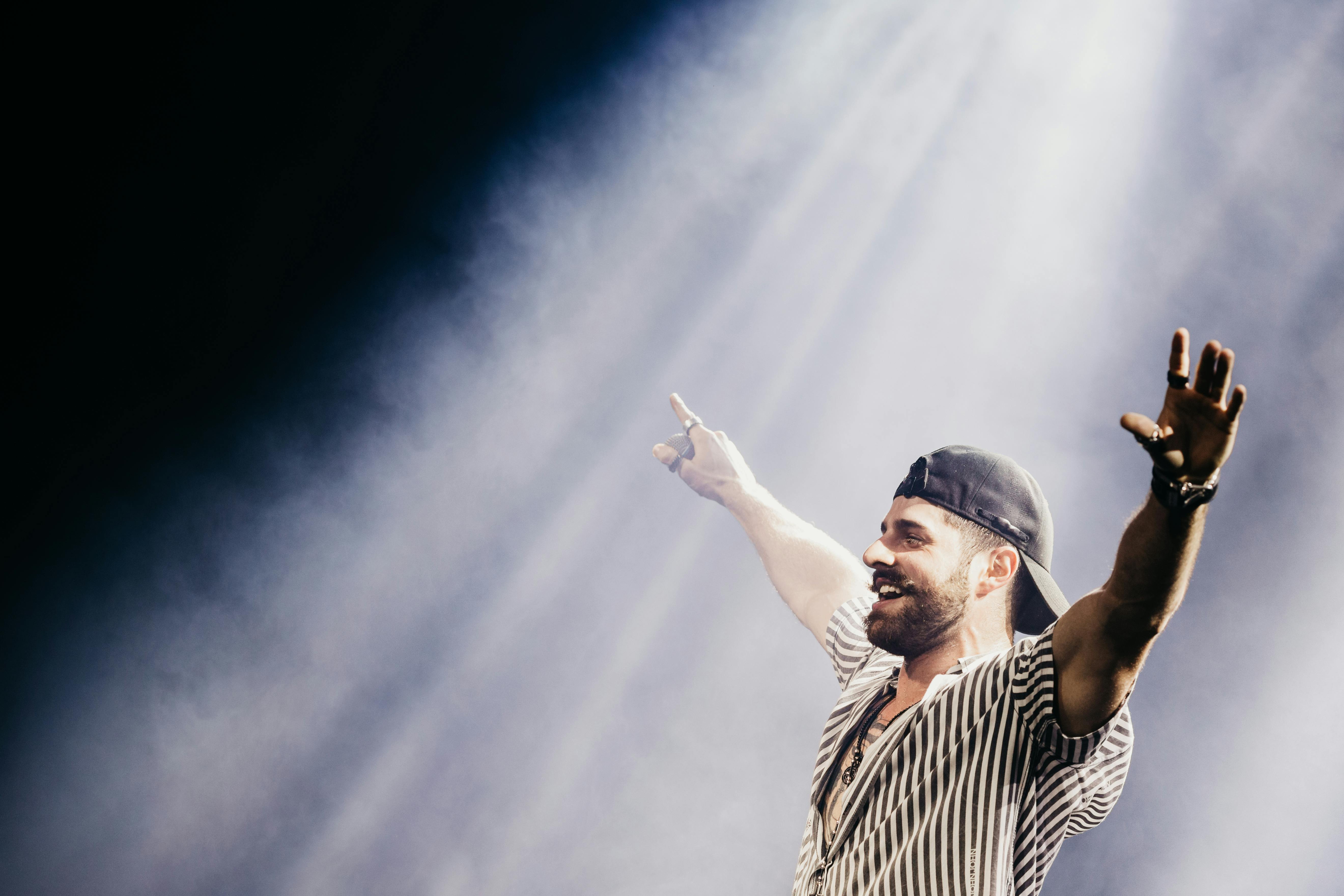 Male singer performing energetically under bright lights at an outdoor music event.