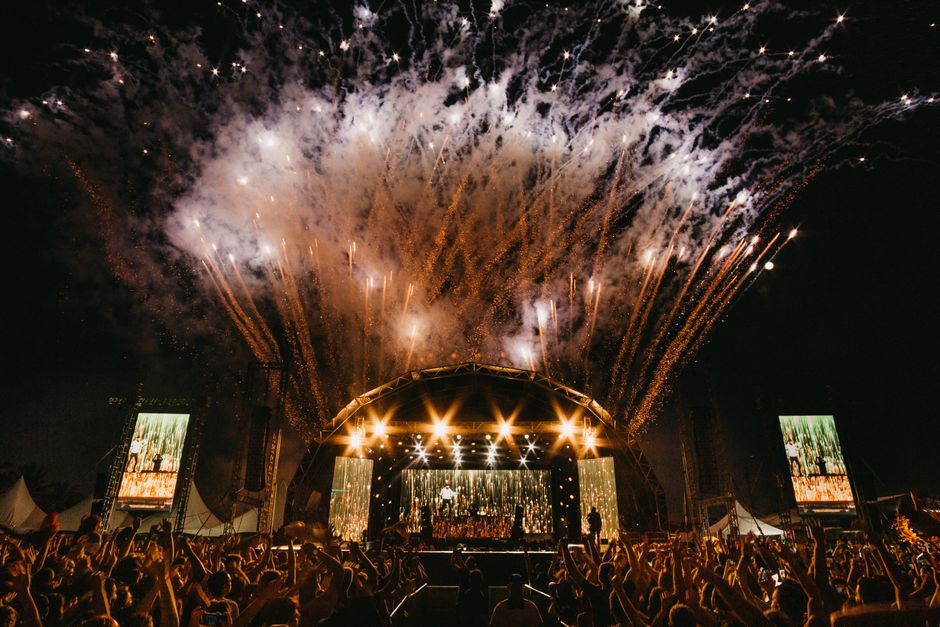 Energetic night concert with dazzling fireworks and a lively crowd outdoors.