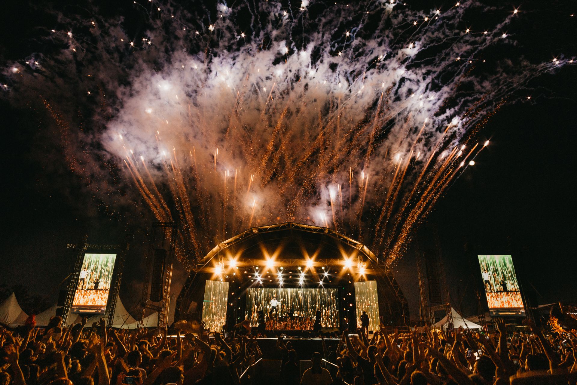 Fireworks display over a concert crowd at night, illustrating the sensory intensity of outdoor events