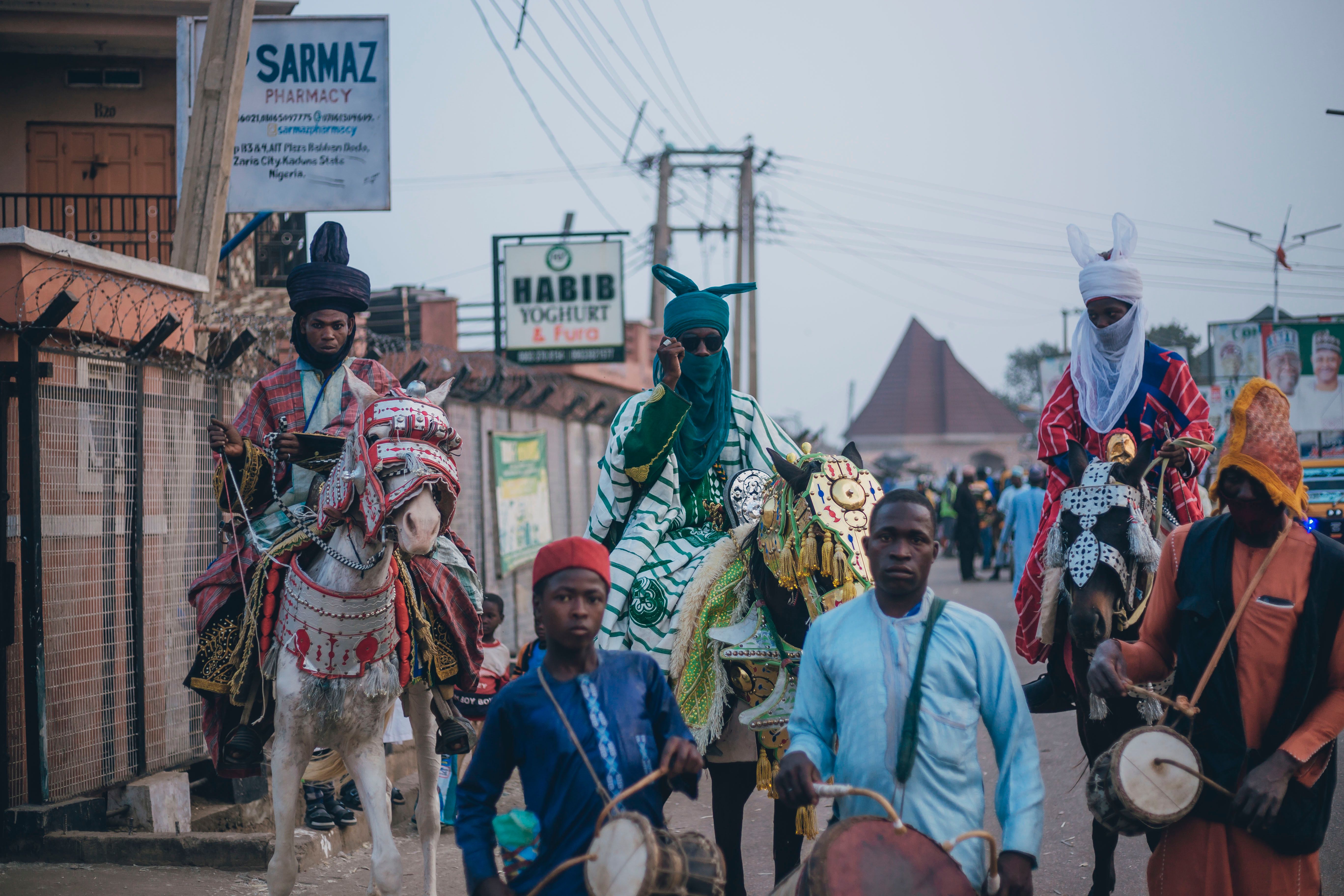 Vibrant street scene with horsemen in traditional attire participating in a Nigerian parade.