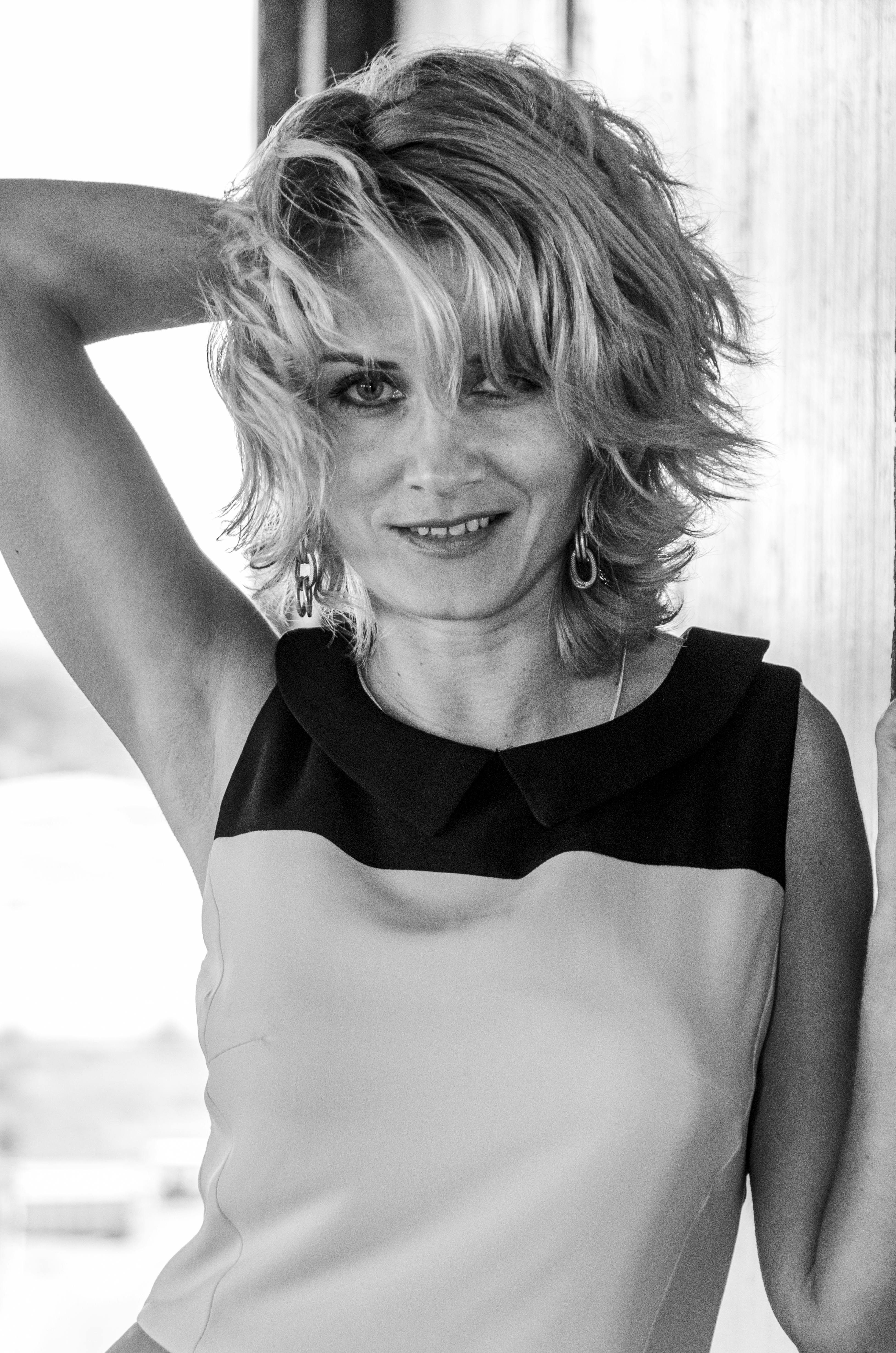 Elegant woman smiling and posing with relaxed confidence in a monochrome image.