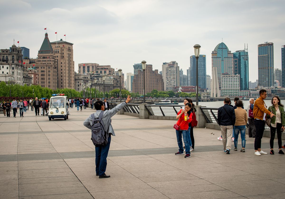 Tourists walking along The Bund with the Shanghai skyline in the background