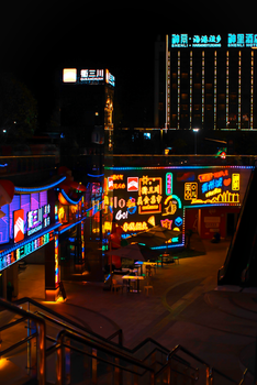 Colorful neon signage lights up the city at night, creating a vibrant urban atmosphere.
