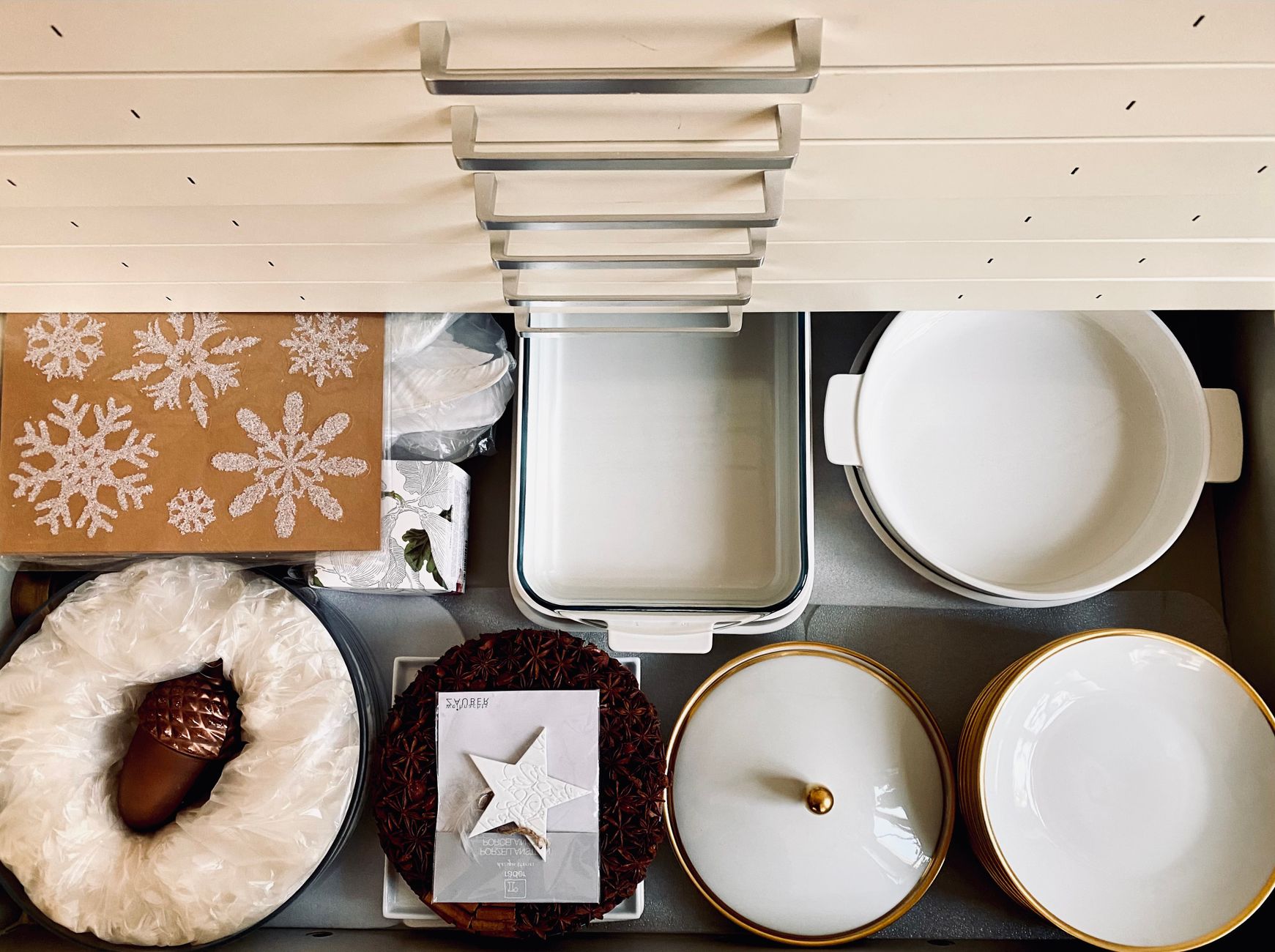 Top view of a kitchen drawer organized with dishes and holiday decorations, creating a neat and festive presentation.
