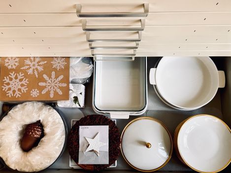 Top view of a kitchen drawer organized with dishes and holiday decorations, creating a neat and festive presentation.