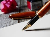 自来水笔在纸上书写的特写，以玫瑰为背景，非常适合优雅的写作主题