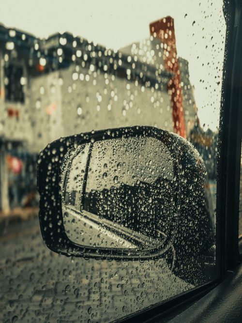 Free Artistic view of a rainy day through a car's side mirror with raindrops. Stock Photo