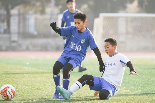 Dynamic scene of young players competing in a soccer match captured in Anhui, China.