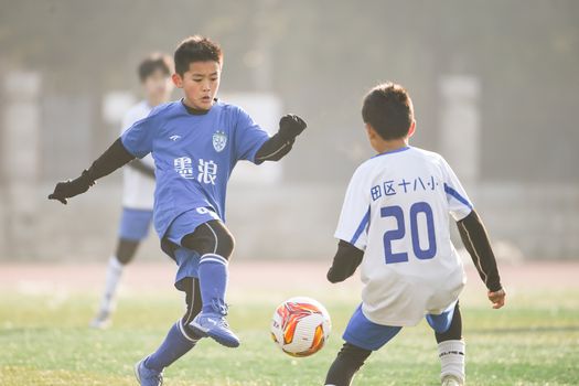 Two young soccer players in action on the field under sunlight. Captured dynamic sports moment.