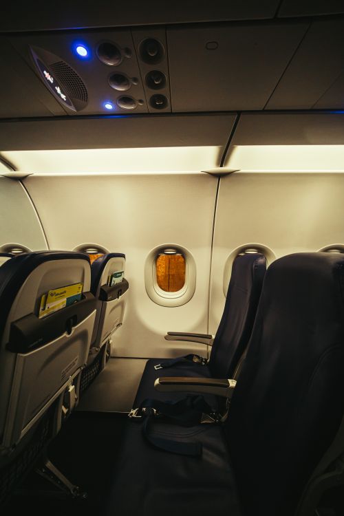 Free Interior of an empty airplane cabin showing seats and a window during flight. Stock Photo