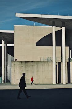 Silhouettes walking by modern urban architecture in bright sun.