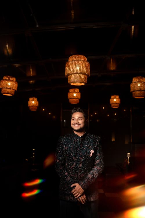 Free A groom in traditional Indian attire smiling under ambient lighting. Stock Photo