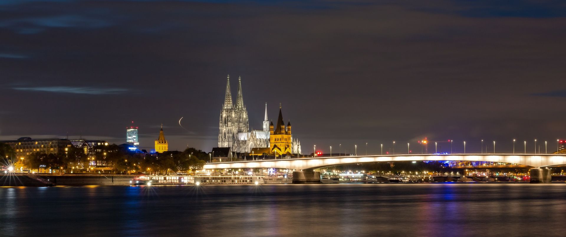 Beautiful night view of Cologne Cathedral and cityscape reflected over the Rhine River.