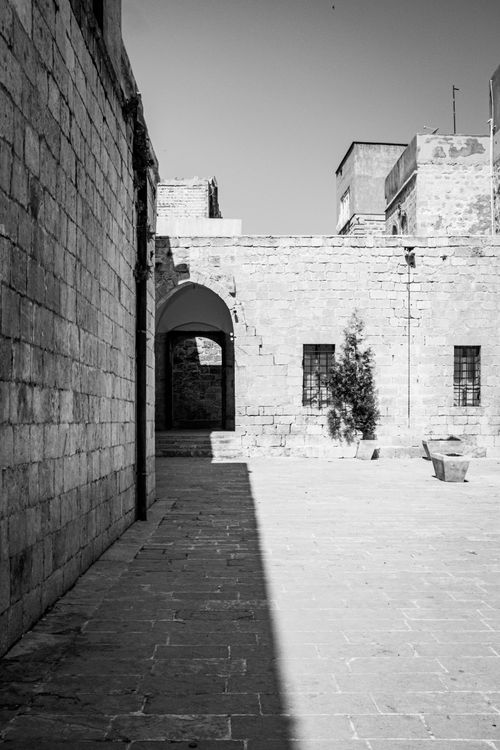 Free Monochrome photo of a historic stone courtyard with architectural details and shadows. Stock Photo