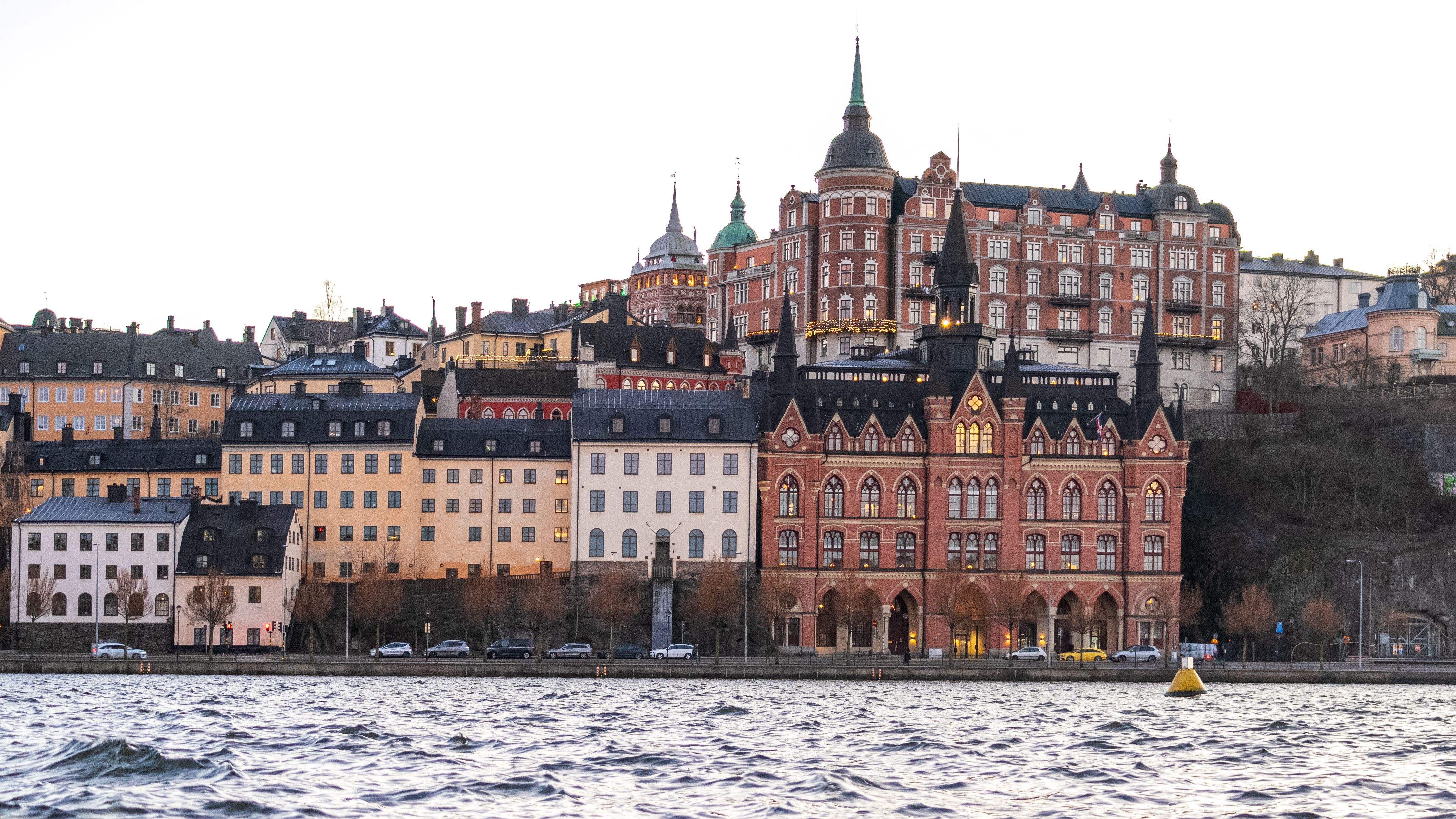 Gratis Utsikt over Stockholms historiske arkitektur ved havnefronten under solnedgang, med Mariabergets ikoniske skyline. Arkivbilde