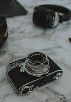 An antique camera and headphones on a white marble surface, perfect for retro tech themes.