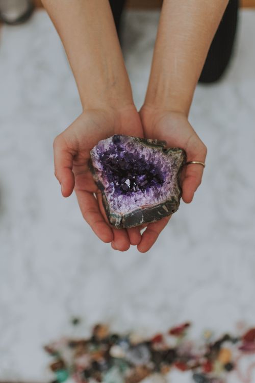 hands holding a purple amethyst geode outdoors in natural light
