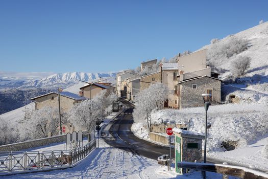 Charming Italian village covered in snow with stunning mountain backdrop.