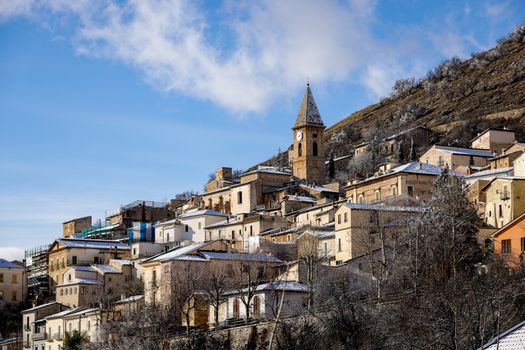 Picturesque Italian village covered in snow during wintertime, showcasing rustic architecture.