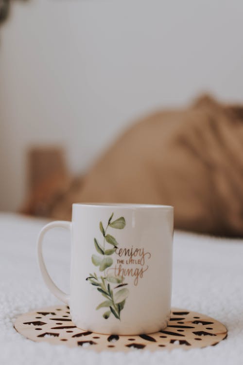 Free White and Green Leaf Graphic Mug on Brown Cutout Base Stock Photo