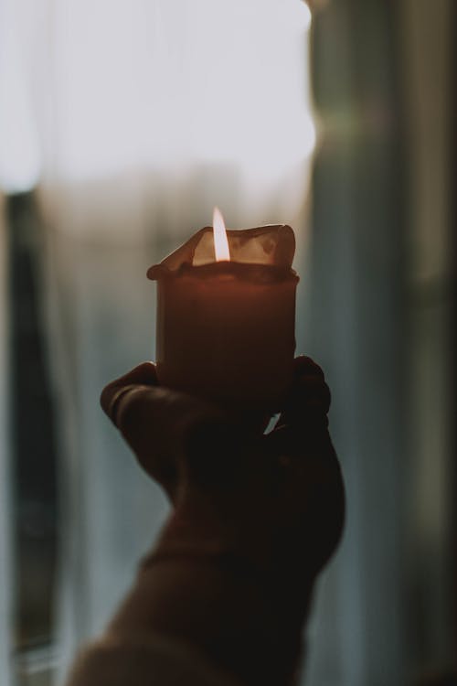 Free Person Holding Lighted Candle in Dark Room Stock Photo