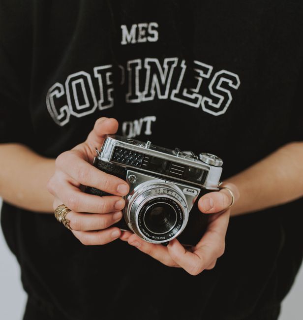 Close-up of hands holding a vintage analog camera, highlighting retro photography.