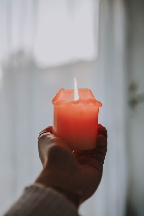 Person Holding Lighted Orange Candle