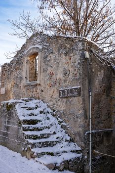 Charming snow-covered ruins of an old stone building in an Italian village during winter.