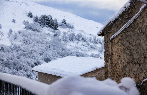 Free Picturesque winter view of a snow-covered village with rustic stone houses and serene landscape. Stock Photo
