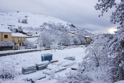 Picturesque snowy village surrounded by hills under a winter sky.