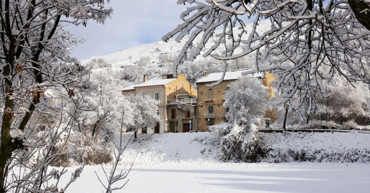 Vue pittoresque d'un village paisible recouvert de neige, entouré d'arbres hivernaux.