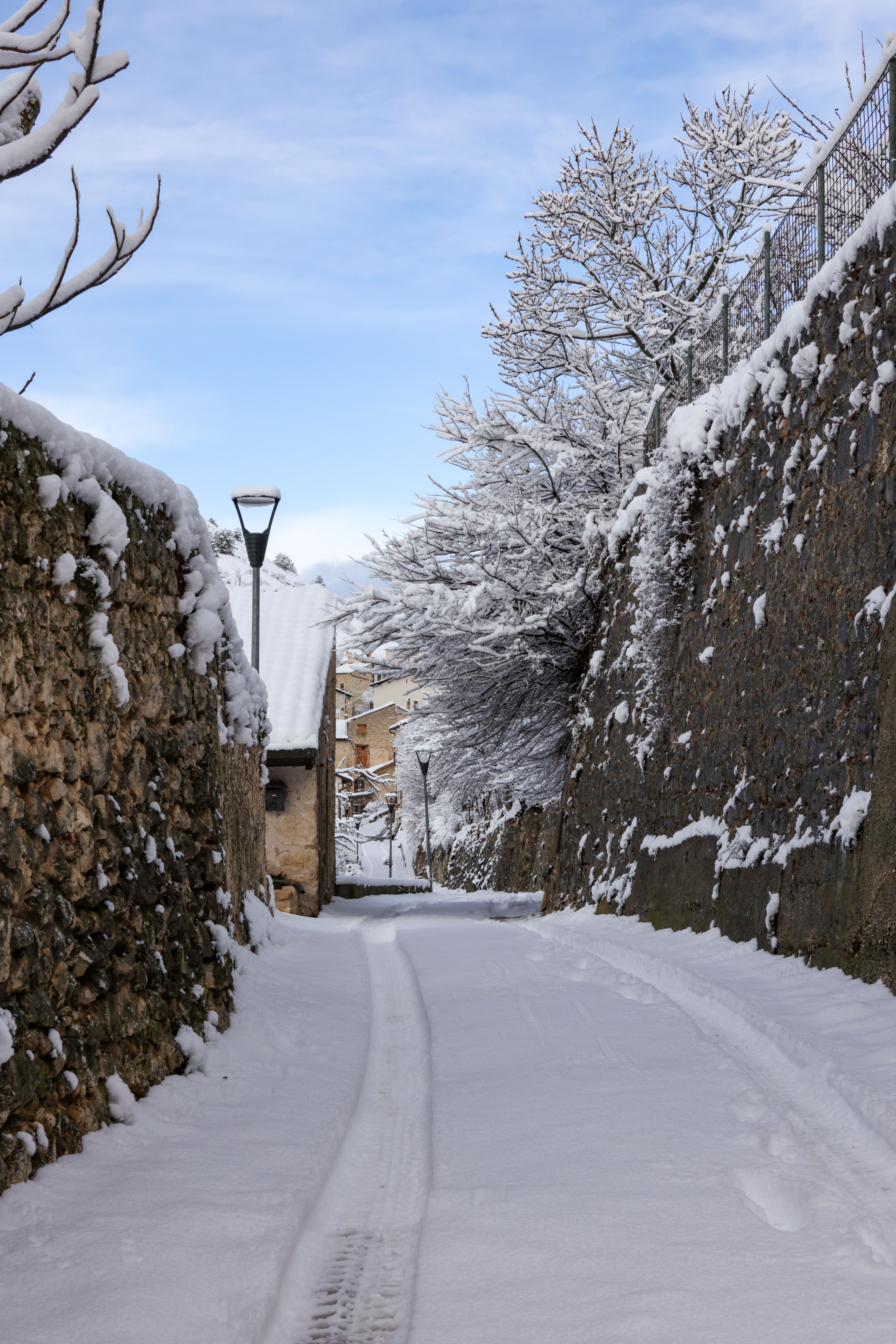 Gratis Vista panoramica di una stradina innevata in un pittoresco villaggio, che crea un paesaggio invernale da favola. Foto a disposizione