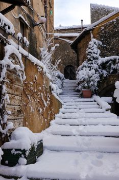 Capture of a quaint village staircase blanketed in fresh winter snow, offering a serene atmosphere.