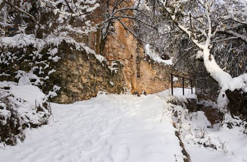 Free A tranquil winter scene with a snow-covered path and ancient stone wall. Stock Photo