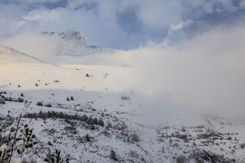 Free A tranquil winter scene showcasing snowy mountains under a blue sky and soft clouds. Stock Photo