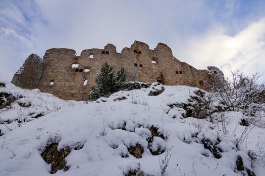 Majestic castle ruins covered in snow under a winter sky.