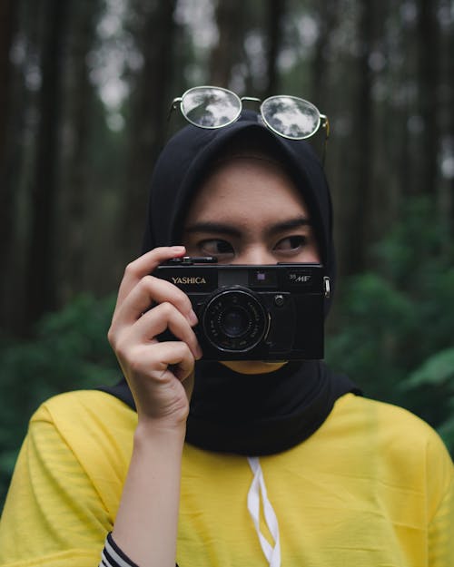 Wanita Dengan Kaos Leher Kru Kuning Memegang Kamera Hitam